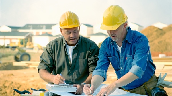 Two contractors with yellow hardhats looking at plans